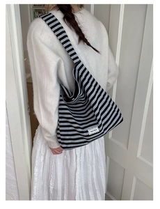 Detail of striped hobo bag featuring wide strap and Beyou Merci patch on a shoulder