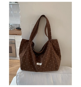 Macro detail of the brown canvas tote bag featuring a white polka dot pattern and label