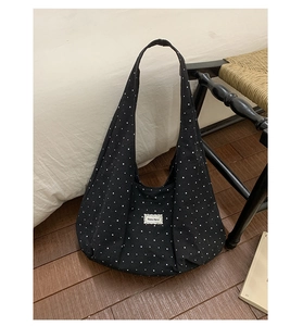 Detail of black canvas tote bag with white star pattern and stylish woven label
