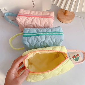 Detailed view of quilted makeup bags in pastel colors with heart patterns and zippers
