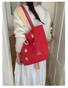 Détail du grand sac cabas en toile rouge avec broderies cartoon et accessoires