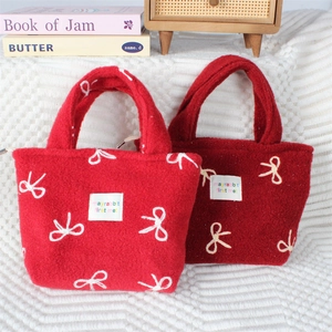 Gros plan du sac cabas en peluche rouge avec broderie nœud blanc et texture duveteuse