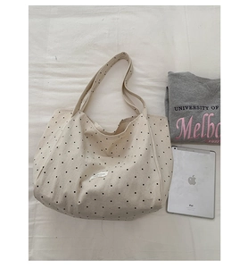 Detailed top view of polka dot canvas tote bag with twin handles on a fabric background
