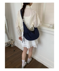 Close-up of navy blue polka dot drawstring bag detail on shoulder with elegant pleats
