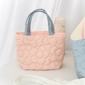 Close-up of floral quilted handbag with pink fabric and blue contrasting handles