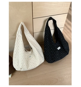 Detailed close-up of polka dot canvas tote bags in black and white on a wooden floor