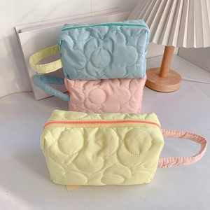 Quilted floral makeup bags in blue, pink, and yellow with side handles and zip closure