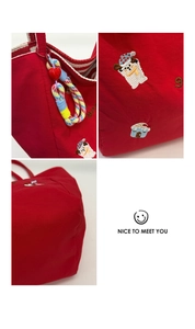 Gros plan du sac cabas rouge avec broderies de dessins animés et breloque en cœur