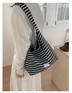 Detail of striped canvas shoulder bag with Beyou Merci label and adjustable wide strap