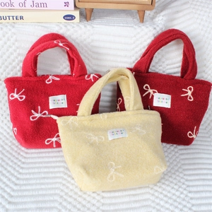 Détail du sac cabas en peluche avec étiquette brodée et nœud décoratif élégant