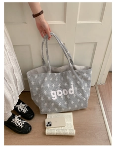 Close-up of grey canvas tote bag with white star print and good letter embroidery