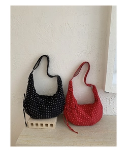 Detail of red and black polka dot crossbody bags with drawstring and metal buckles
