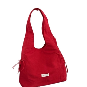 Red large capacity nylon tote bag with drawstring bow knots and a central white logo label