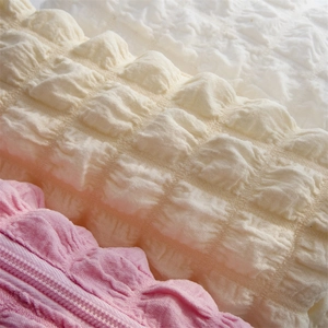 Close-up of soft popcorn bubble texture fabric pencil pouches in pink, beige and white