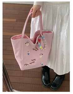Détail du cabas en toile rose avec broderie de chien et sangle tressée colorée