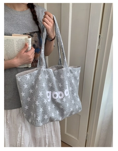 Detail of grey canvas tote bag with white star pattern and good lettering print