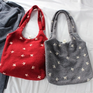 Detail of embroidered bow patterns on wool tote bag with classic checkered lining