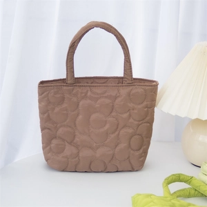 Close-up of brown quilted handbag featuring detailed floral stitching and soft handles
