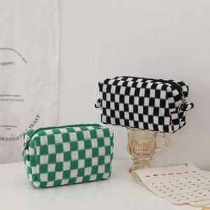 Detail of checkered knit cosmetic bags in black and green with zip closure and soft texture