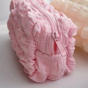 Close-up of pink seersucker fabric texture and zipper detail on puffy pencil case