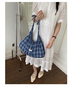 Close-up of blue and white checkered canvas tote bag with pleated texture and label