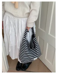 Detail of striped tote bag with adjustable strap and brand label on soft fabric