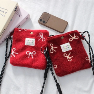 Detail of red plush floral shoulder bag with bow embroidery and metal snap closure