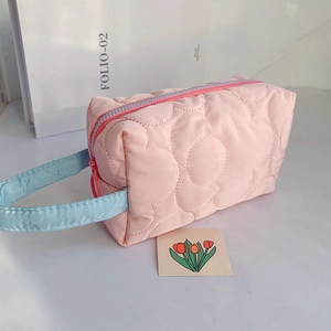 Detailed close-up of quilted floral cosmetic bag with pink body and blue handle