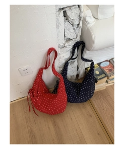 Close-up of polka dot crescent bags in red and navy with drawstring and adjustable straps