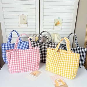 Close-up of checkered canvas lunch bags in pink, yellow, blue, and black grid patterns