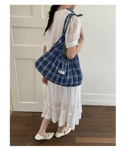 Detail shot of blue and white checkered canvas tote bag with woven brand label decoration