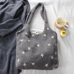 Close-up of embroidered bow tote bag with metallic clasp and checkered inner lining