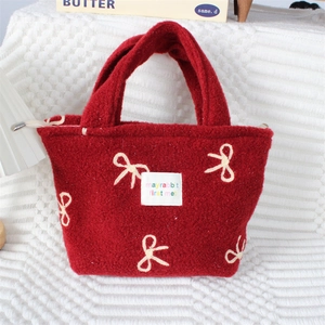 Détail du sac à main en peluche rouge avec nœuds brodés et texture polaire douce