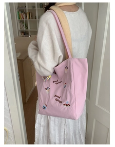 Détail du sac cabas en toile rose avec broderies de chiot et de cupcake colorés
