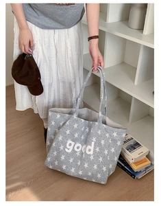 Close-up of grey canvas tote bag with white star patterns and 'good' letter print