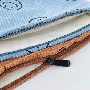 Macro view of corduroy makeup bag detailing texture, black zipper, and white fabric lining