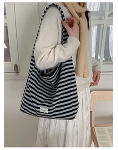 Close-up of a large canvas striped tote bag with adjustable strap and lace label detail