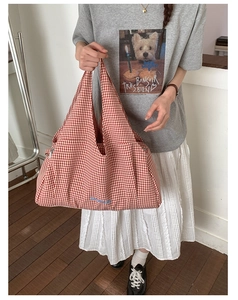 Detail of red checkered canvas tote bag with blue embroidered letters and side pleats