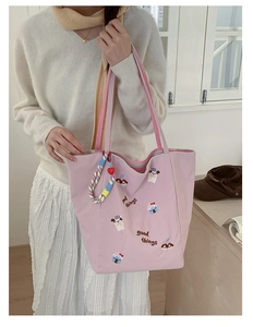 Détail d'un cabas rose en toile avec broderie de chien et poignées rayées au style épuré