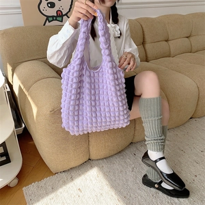 Detail of light purple popcorn fabric tote bag held by model in cozy interior setting