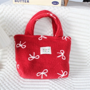 Détail du sac à main en peluche rouge avec broderies nœuds blancs et étiquette cousue