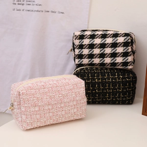 Three elegant tweed vanity bags in pink and black patterns with gold accents and zippers