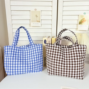 Close-up of blue and brown checkered canvas tote bags on a desk with a warm desk lamp