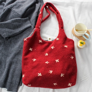 Detail of red wool tote bag featuring white bow embroidery and checkered lining