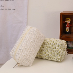 Close-up of tweed makeup bag showing thick woven texture and metal zipper detail