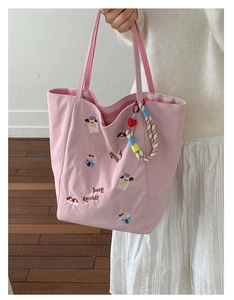 Détail du cabas en toile rose avec broderie de chien et texte décoratif doux