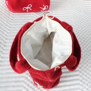 Détail du sac à main en peluche rouge avec broderie nœud blanc et intérieur zippé
