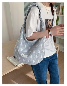 Detail of grey crossbody bag featuring white star print and gathered ruffle shoulder strap