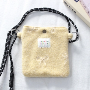 Detail of yellow plush mini crossbody bag with woven strap and cute embroidery label