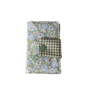Floral fabric book cover with green pattern and button closure in a minimalist style